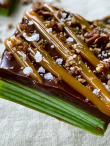 Top-down view of caramel apple bark with dark chocolate, caramel drizzles, and toasted pecans on a cream linen background.