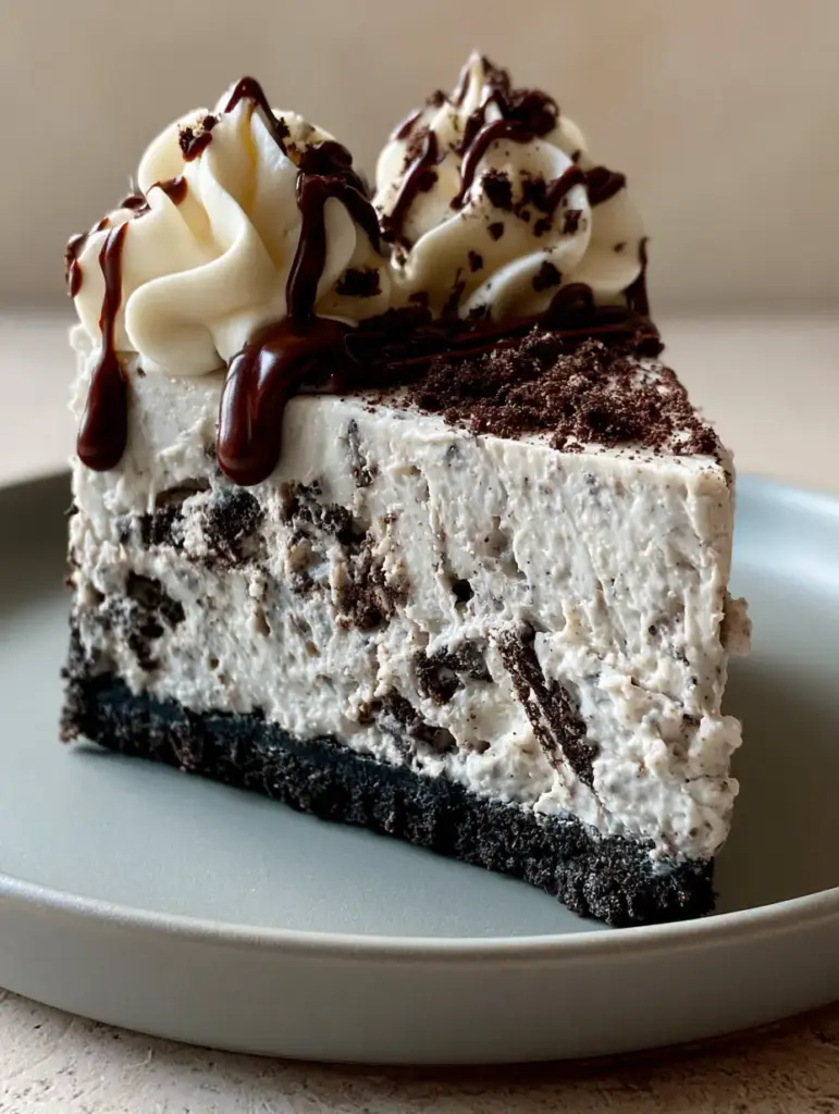 A close up of piped vanilla whipped cream rosettes with a rich dark chocolate drizzle on an Oreo cheesecake.