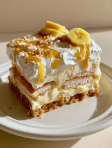 Eye-level shot of a banana pudding ice cream cake slice with golden caramel sauce drizzle and fresh bananas.