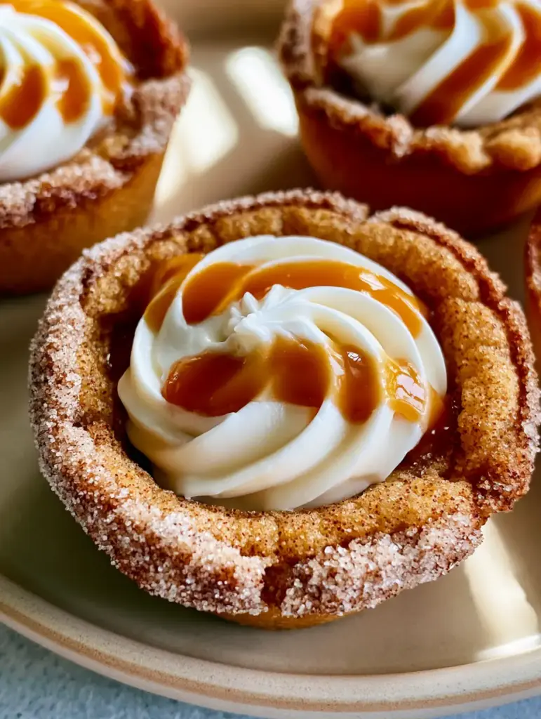 A detailed close-up showing the glossy amber caramel drizzle on top of pure white frosting. (snickerdoodle cookie cups)