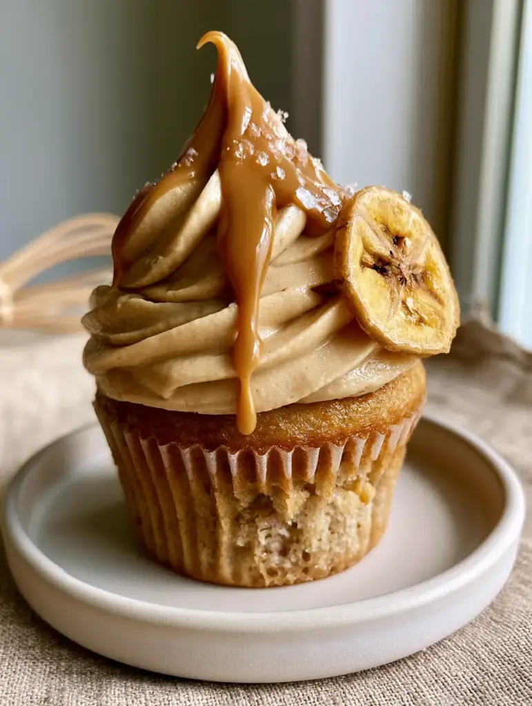 Peanut Butter Banana Cupcakes with Silky Smooth Frosting 1 Eye-level shot of a Peanut Butter Banana Cupcake featuring a glossy warm peanut butter drizzle and sea salt dusting.