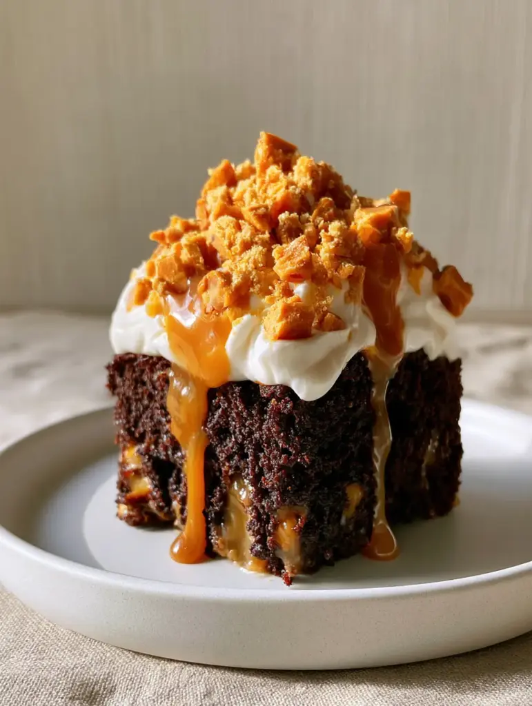Butterfinger Cake: The Ultimate Moist Chocolate Caramel Poke Cake Recipe 1 Side view of a chocolate Butterfinger cake slice showing the thick whipped cream and caramel drizzle. (Butterfinger cake)