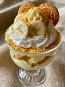 Close-up handheld smartphone photo showing layers of thick vanilla custard and softened wafers in a Chick-Fil-A banana pudding.