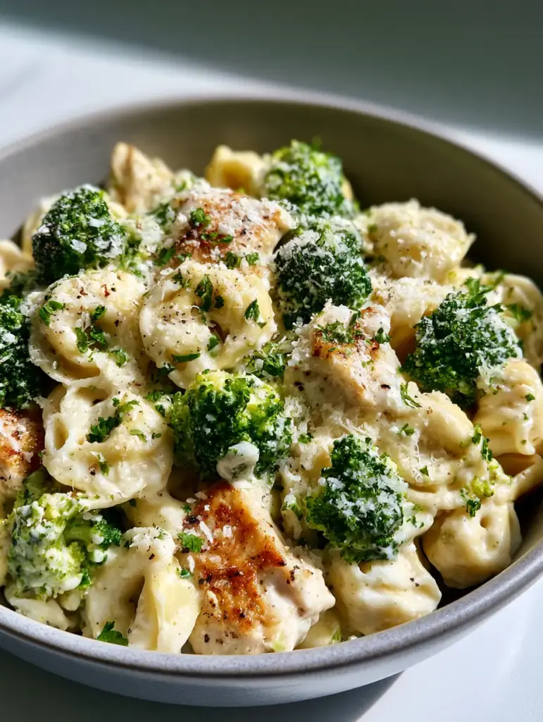 Detailed shot of plump tortellini in rich garlic cream sauce with seared chicken and fresh parsley.